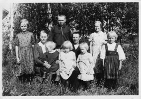 Mikko Ampuja ja Lyyli Ampujan perhekuva Etu-Helkalan pihassa. Vasemmalta Pirkko (1926-2004), Lyyli-äiti ja hänen sylissä Elli (1934- ), Pentti (23.10.1921 Vahviala - 19.11.1991 Iitti), Mikko-isä ja hänen sylissä Liisa (1930-2009) ja Aira (1931-2020), Marjatta (1923-2004) ja Annikki (1928- ). Mikko viljeli tilaansa ja Lyyli hoti kotityöt ja lapset. Vanhakylä Etu-Helkala 1936 (Veikko Ampuja)